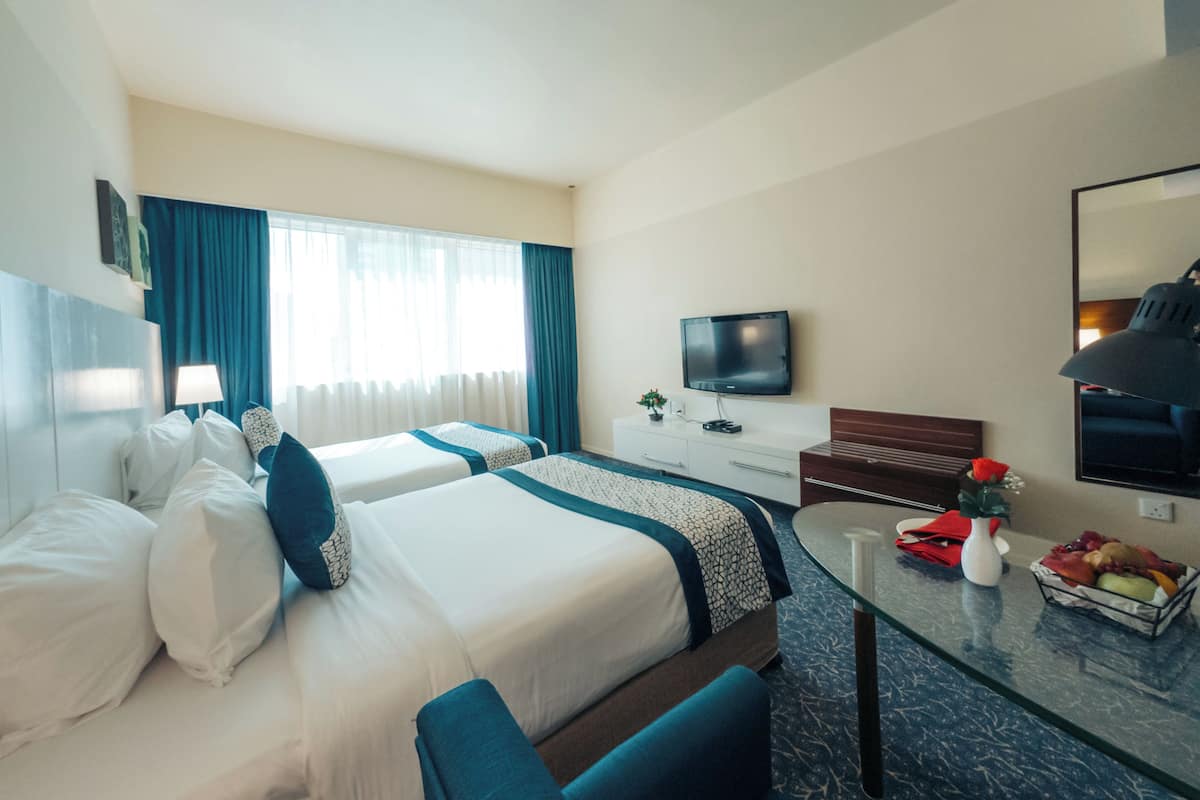 Une chambre d’hôtel avec deux lits, une télévision, un bureau et une table à manger.