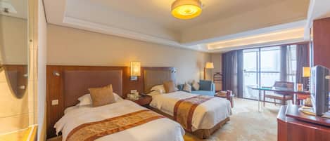 A hotel room with two beds, a desk, a chair, a TV, and a large window.