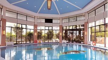 A large indoor swimming pool with a high ceiling and large windows.