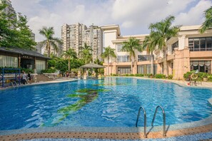 Una piscina rodeada de palmeras y edificios modernos.