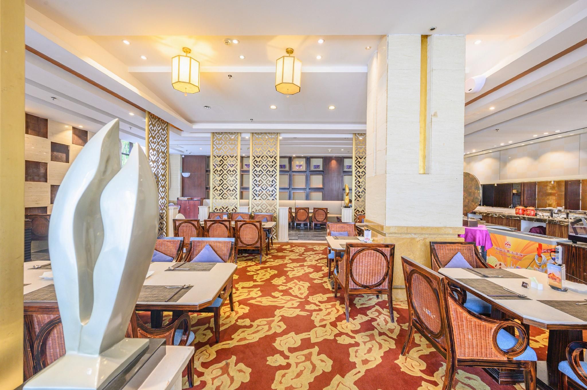 Ein Hotel-Speisesaal mit mehreren Tischen und Stühlen, einem gemusterten Teppich und dekorativen Wandverkleidungen.