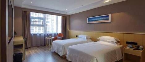 A hotel room with two beds, a desk, a chair, and a window with curtains.