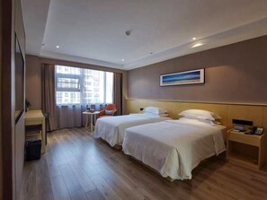 A hotel room with two beds, a desk, a chair, and a window with curtains.