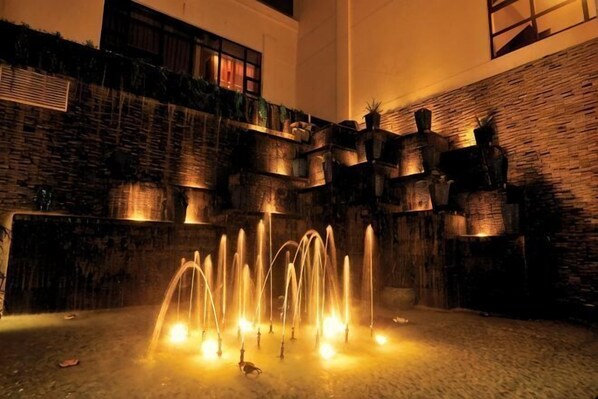 Ein Innenhof mit Brunnen, Ziegelmauern und Blumentöpfen.