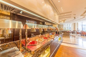 A buffet area with multiple food stations, a kitchen area, and a seating area with tables and chairs. - Xiamen Zhongwei Gulangwan hotel (Xiamen)