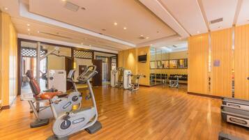 A gym with cardio machines, weight benches, and mirrors.