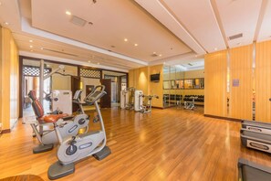 A gym with cardio machines, weight benches, and mirrors.
