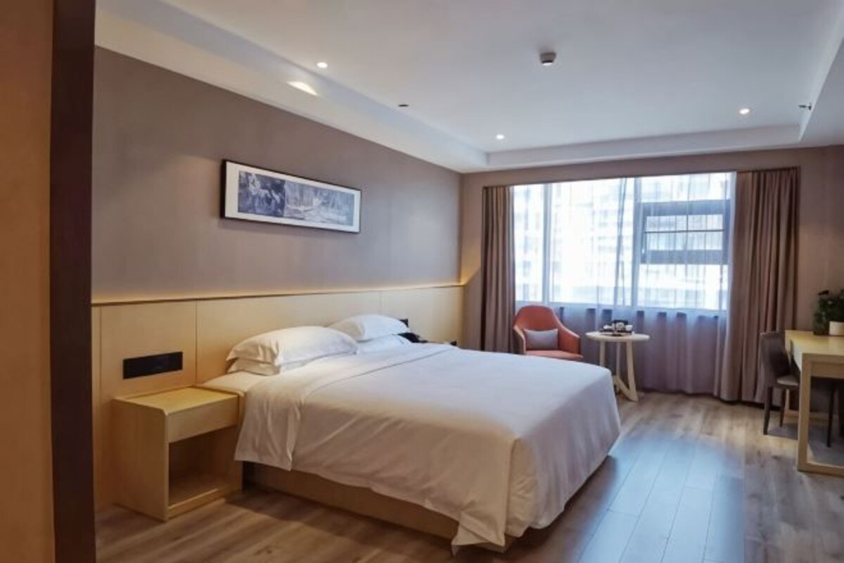 Una habitación de hotel con cama, mesita de noche, silla y una pequeña mesa con una planta.