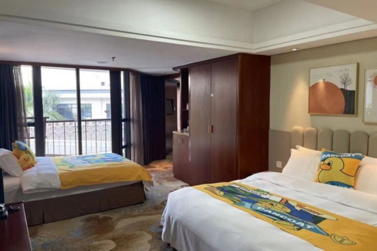 Habitación de hotel con dos camas, un armario, un televisor y vistas al exterior.