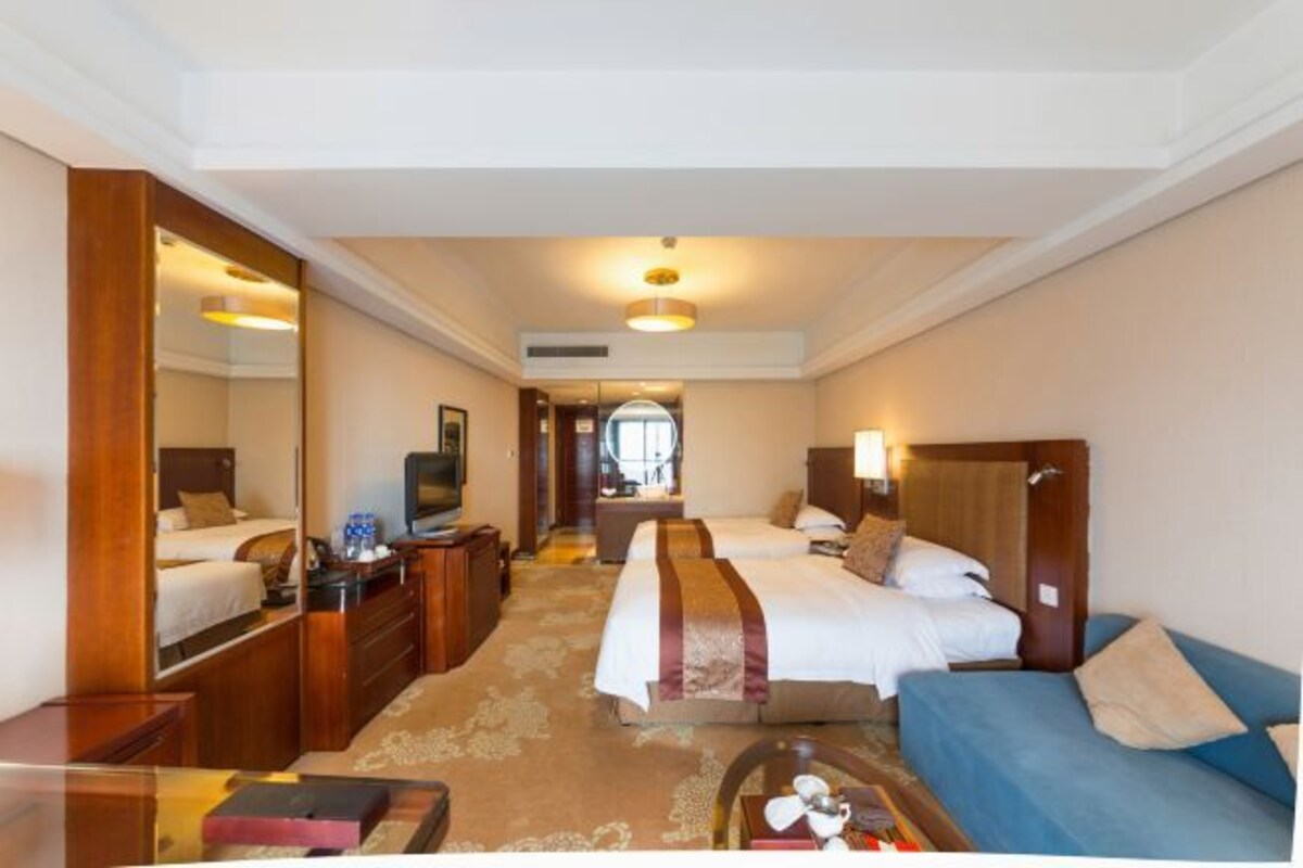 Habitación de hotel con dos camas, un sofá, un escritorio y una televisión.