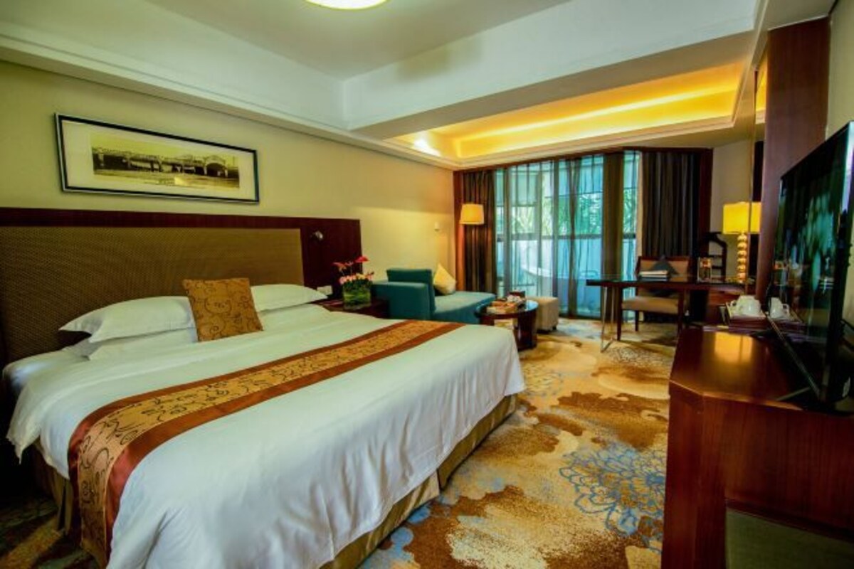 Una habitación de hotel con una cama grande, un escritorio, una silla y un televisor.