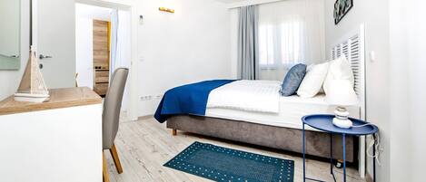 A modern bedroom with a bed, bedside table, and a desk with a chair.