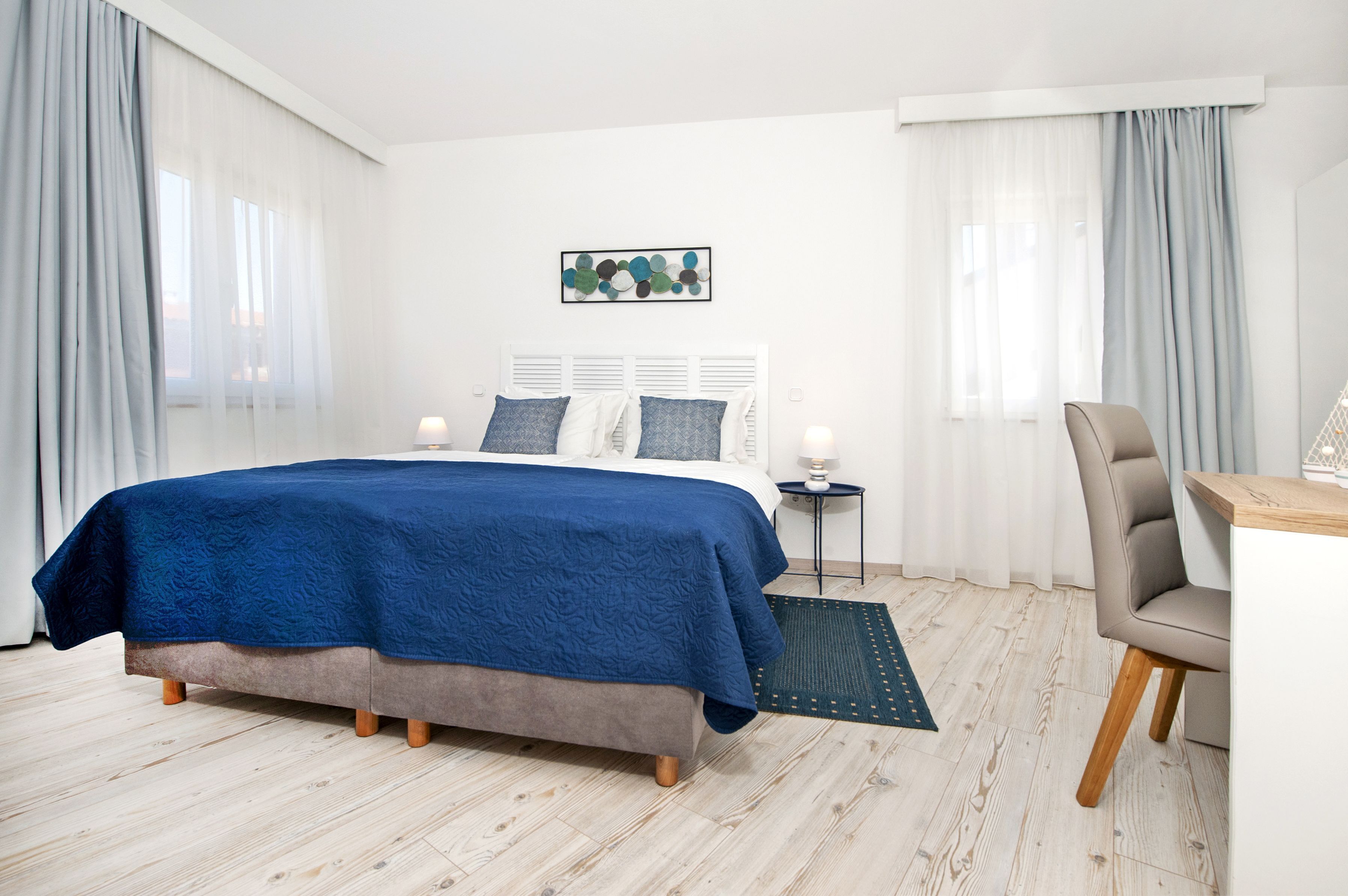Une chambre à coucher avec un lit, une chaise, une petite table et un tableau au mur.