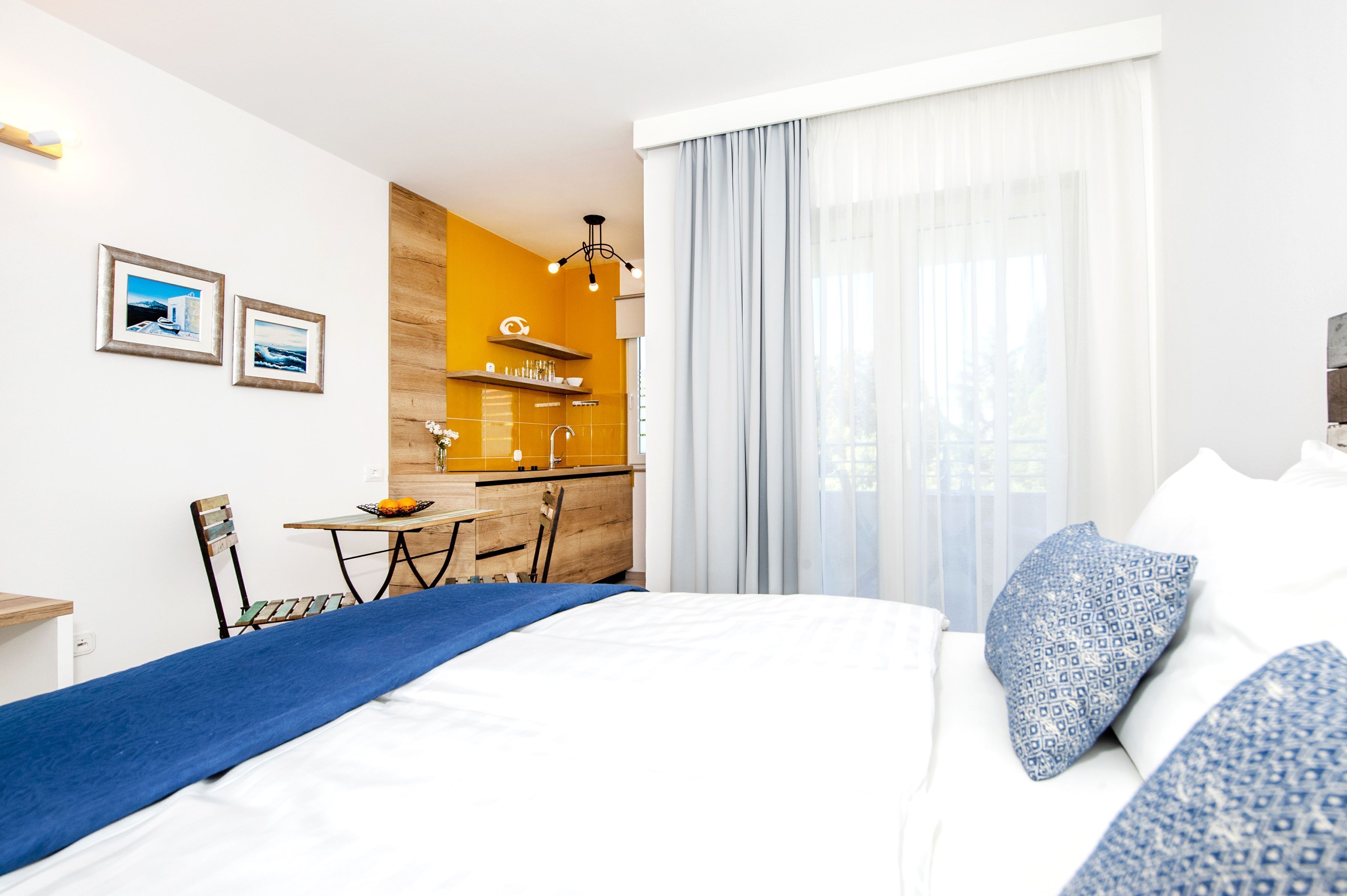 Ein Hotelzimmer mit Bett, Schreibtisch, Stuhl und einer Küchenzeile.