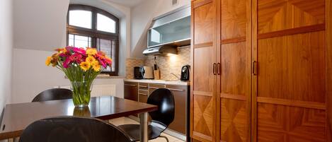 A modern kitchen with wooden cabinets, a dining table with chairs, and a vase of flowers.