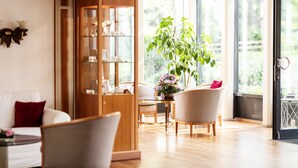 Un salon moderne avec un meuble en bois, une table à manger et une grande fenêtre donnant sur un paysage verdoyant.