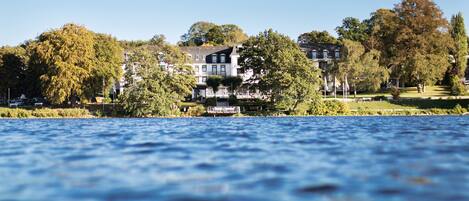 A lakeside hotel with multiple buildings, a dock, and lush greenery.