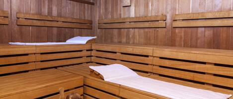 Uma sauna com bancos e assentos de madeira, paredes de madeira e um balde de madeira.