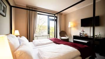 Una habitación de hotel con una cama grande, un escritorio, una silla, un televisor y una ventana con cortinas.