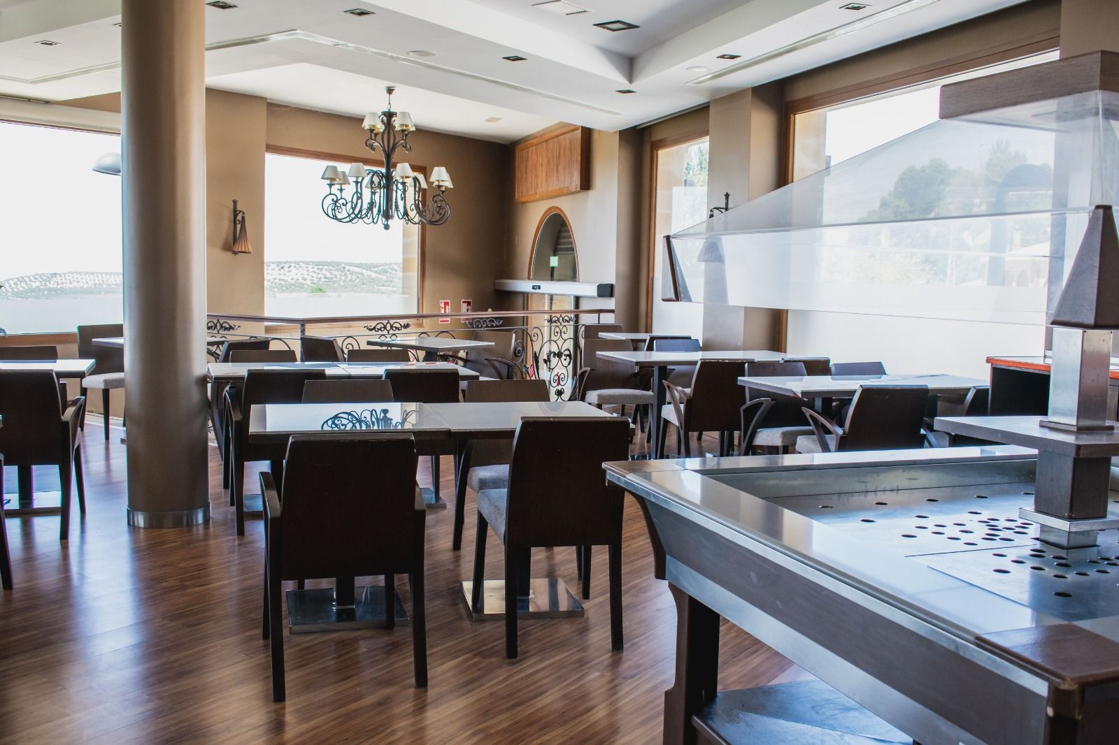 Un restaurante con piso de madera, mesas, sillas, una parrilla grande de acero inoxidable y un candelabro.