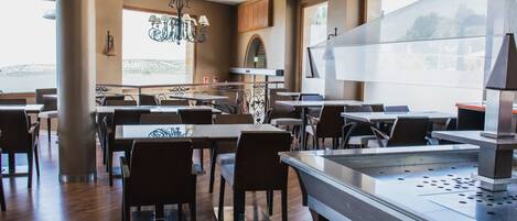 Un restaurante con piso de madera, mesas, sillas, una parrilla grande de acero inoxidable y un candelabro.