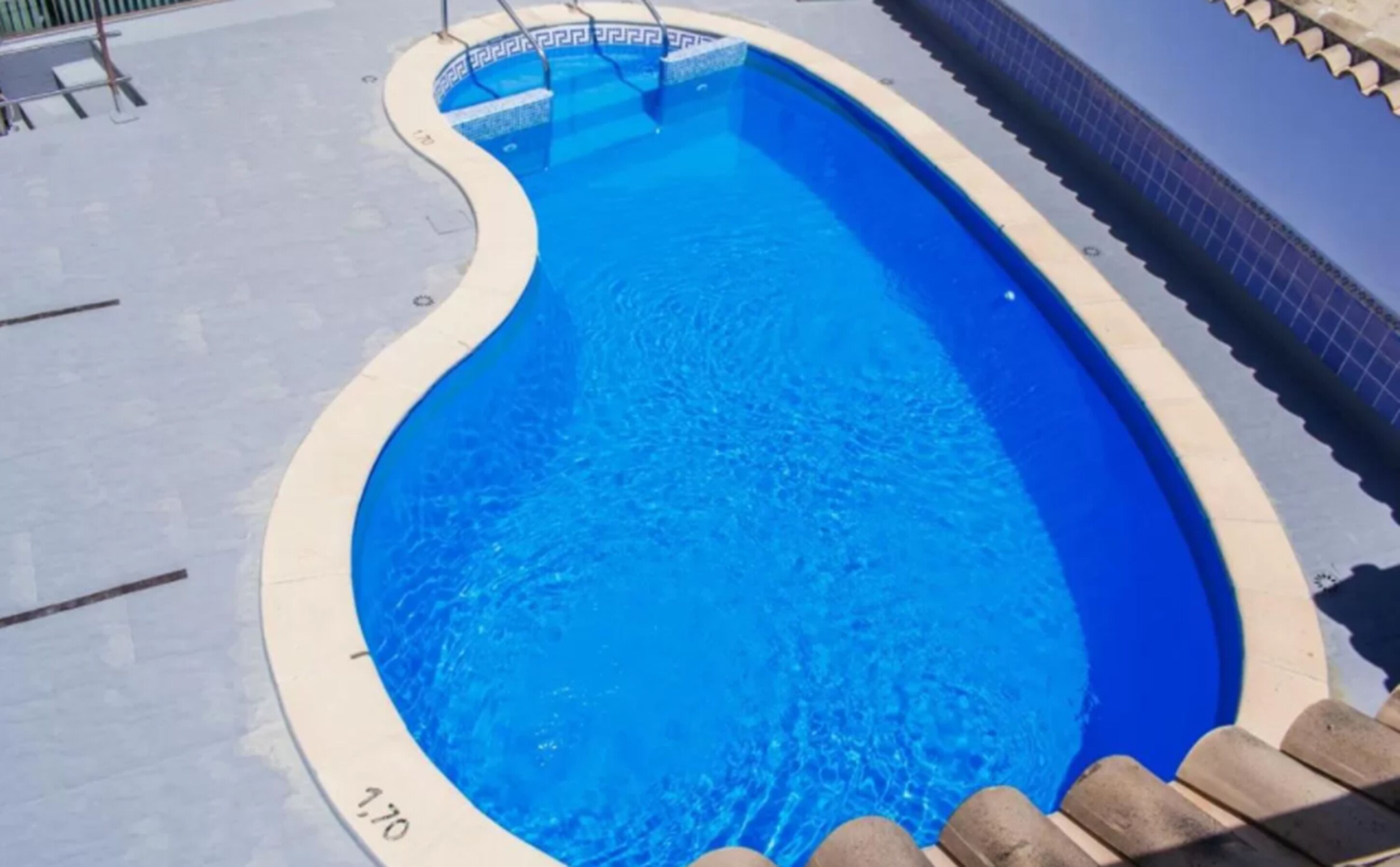 A swimming pool with a curved edge and a tiled border.