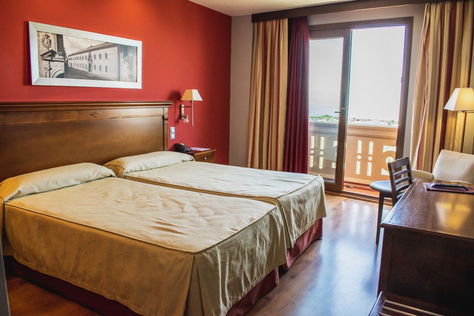 A hotel room with two beds, a desk, a chair, a lamp, a phone, and a window with curtains.
