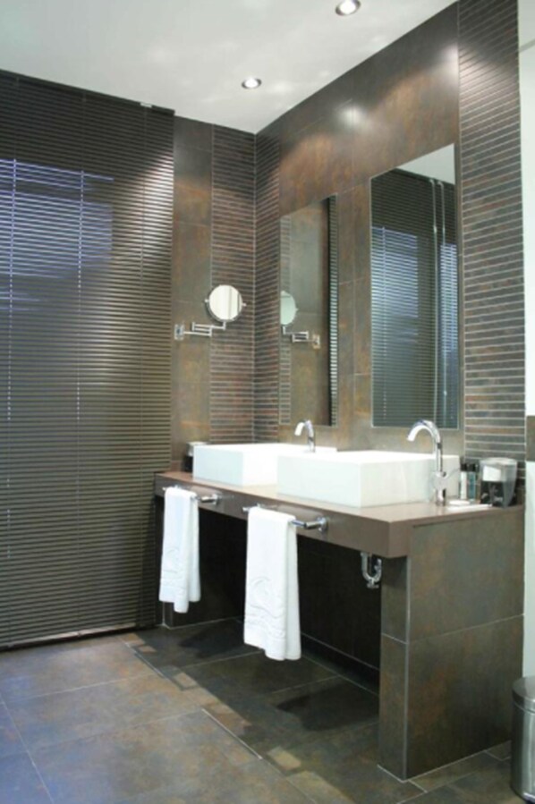 Un baño moderno con un espejo grande, dos lavamanos y un perchero para toallas.