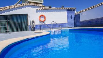Una piscina con un flotador salvavidas, una escalera metálica y un muro de azulejos.