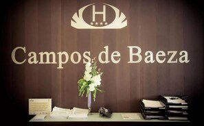 A reception desk with a sign reading "Campos de Baez" and a logo above it. - Campos de Baeza (Baeza)