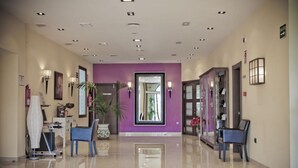 A hotel lobby with a purple accent wall, a reception desk, seating areas, and a glass door entrance. - Campos de Baeza (Baeza)