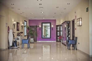 A hotel lobby with a purple accent wall, a reception desk, seating areas, and a glass door entrance. - Campos de Baeza (Baeza)