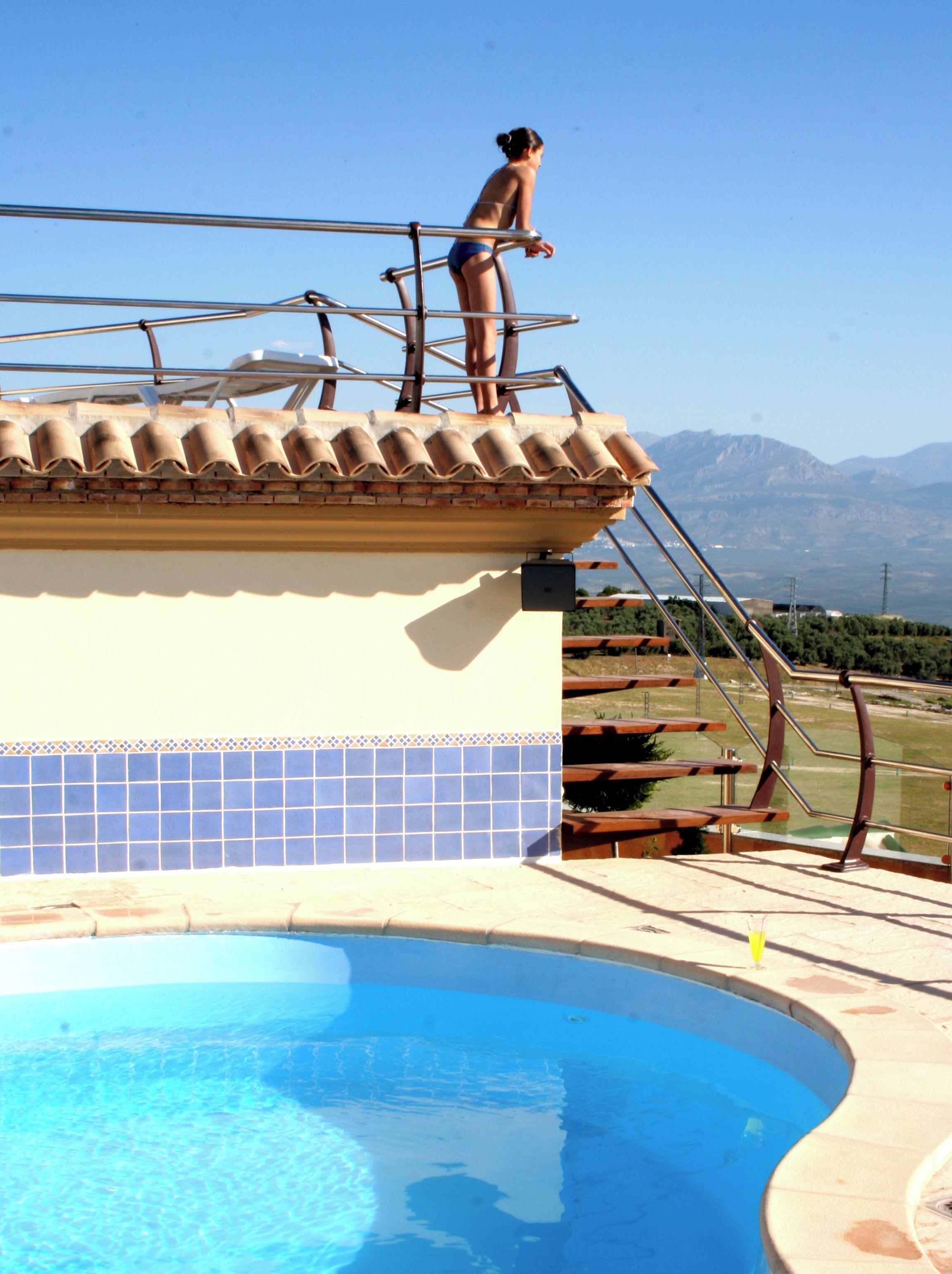 Une piscine dotée d’un plongeoir et offrant une vue sur les montagnes en arrière-plan.