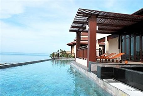 Una piscina al aire libre, sombrillas, sillones reclinables de piscina