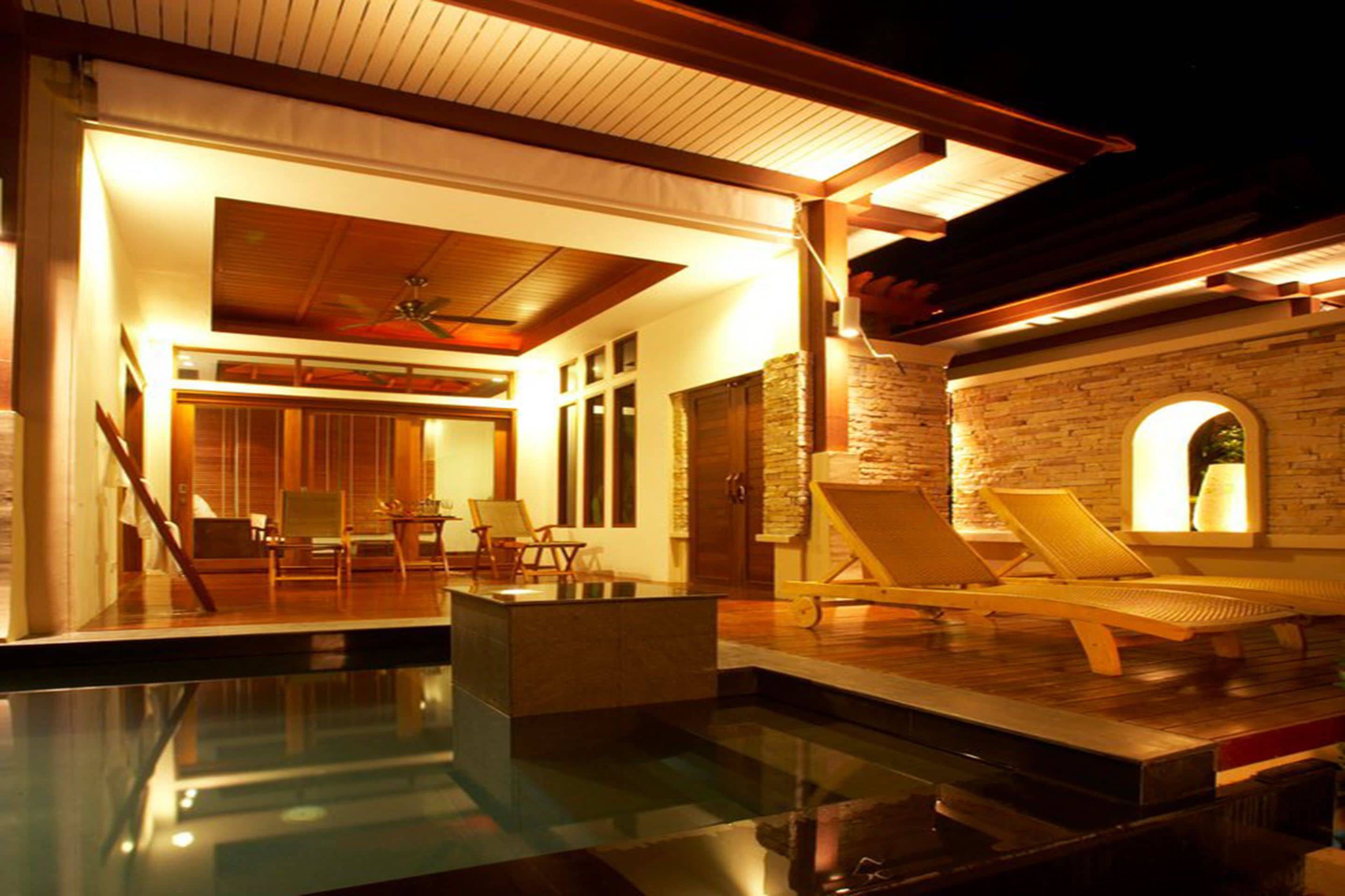 A modern indoor pool area with lounge chairs and a stone wall.