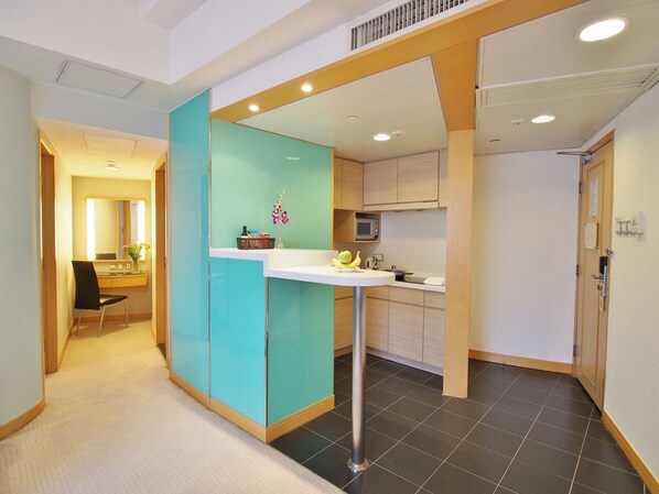 A modern kitchen with a white countertop, a microwave, and a sink. There is a teal-colored cabinet and a door leading to another room. - Garden View Hong Kong (Hong Kong)
