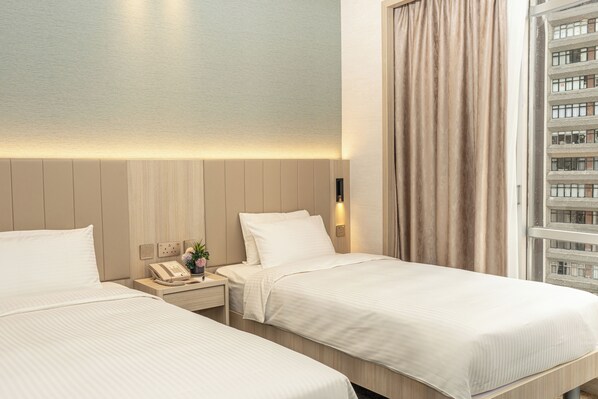 A hotel room with two beds, a bedside telephone, and a window with curtains. - Garden View Hong Kong (Hong Kong)