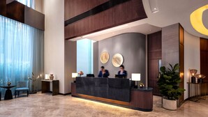 A modern reception area with a marble reception desk, two receptionists, and a large potted plant. - Garden View Hong Kong (Hong Kong)