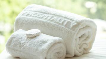 Une serviette blanche roulée, sur laquelle le mot « HOSPITALITY » est imprimé en relief, est posée sur un lit.