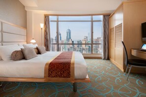 A hotel room with a large bed, a desk, and a view of a city skyline. - Garden View Hong Kong (Hong Kong)