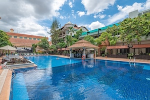 Een buitenzwembad, parasols bij het zwembad en ligstoelen
