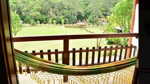 A hammock on a balcony with a view of a lush garden and a small house in the distance. - Spazio di Garda (Sao Roque)