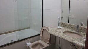 A bathroom with a glass shower enclosure, a toilet, and a sink with a granite countertop. - Spazio di Garda (Sao Roque)