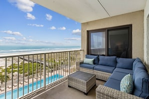 Varanda com vista para o mar, piscina e sofá azul.