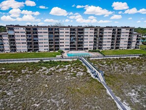 A multi-story residential building with balconies, a swimming pool, and a grassy area.