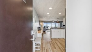 A modern kitchen with white cabinets, a wooden floor, and a view to the outside.