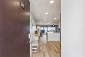 A modern kitchen with white cabinets, a wooden floor, and a view to the outside.