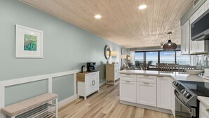 A modern kitchen with white cabinetry, a central island, and a view to the outside.