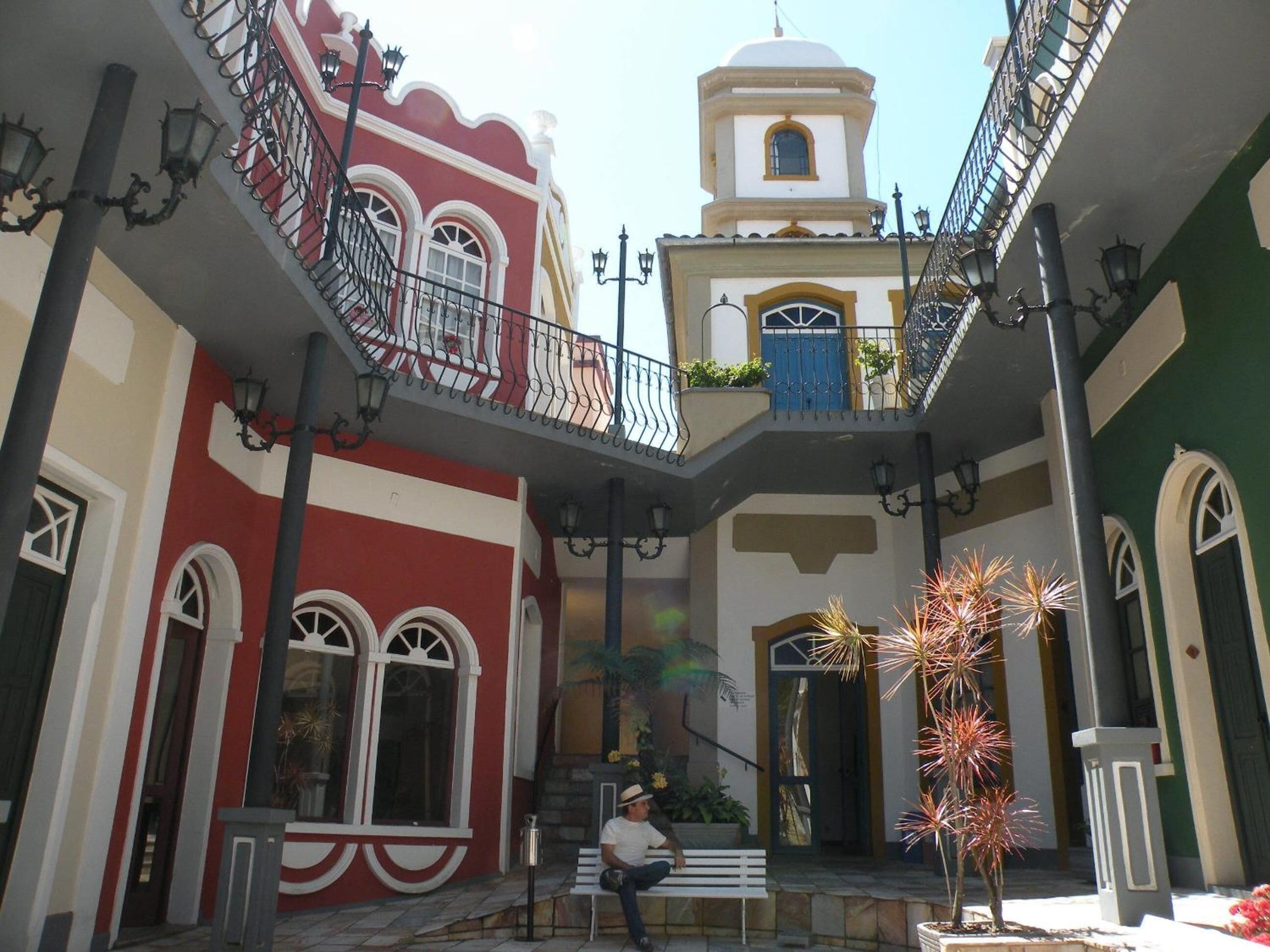 Un patio con un banco, una pequeña fuente y un edificio con balcón.