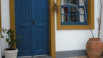 A blue door with a window, a potted plant, and a large terracotta pot.